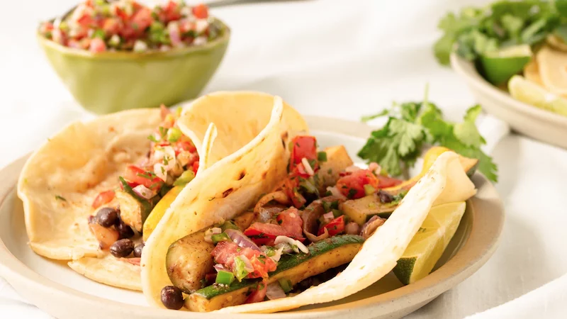 2 zucchini Fajitas on a plate with a bowl of salsa